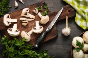 Sliced mushrooms and ingredients for cooking at dark wooden table. Space for text. Ingredients for cooking food background.